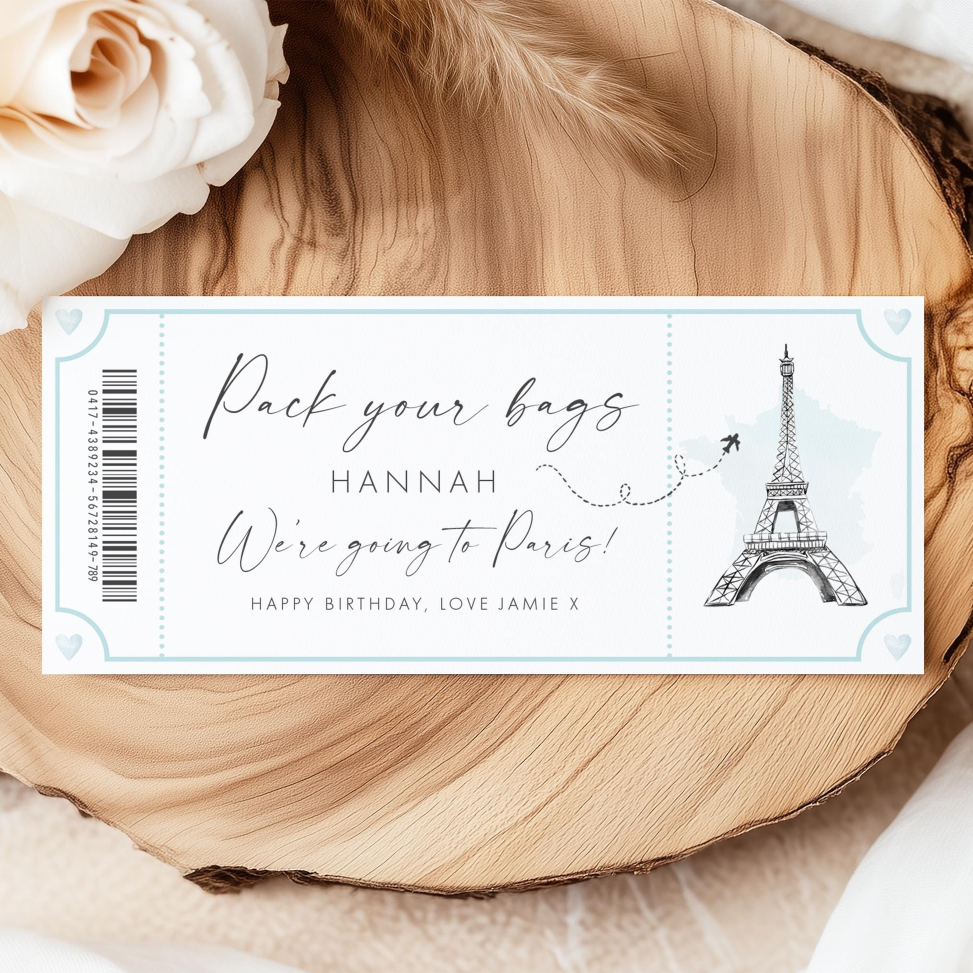 A ticket-like design with a Paris Eiffel Tower illustration, along with the text "Pack your bags Hannah We're going to Paris!" and "Happy Birthday, Love Jamie X".