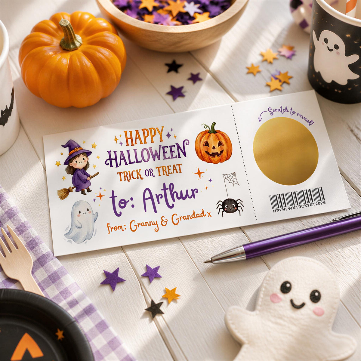 a Halloween-themed card with a pumpkin, ghost, spider, and other spooky decorations, along with a pen and a small ghost figure.