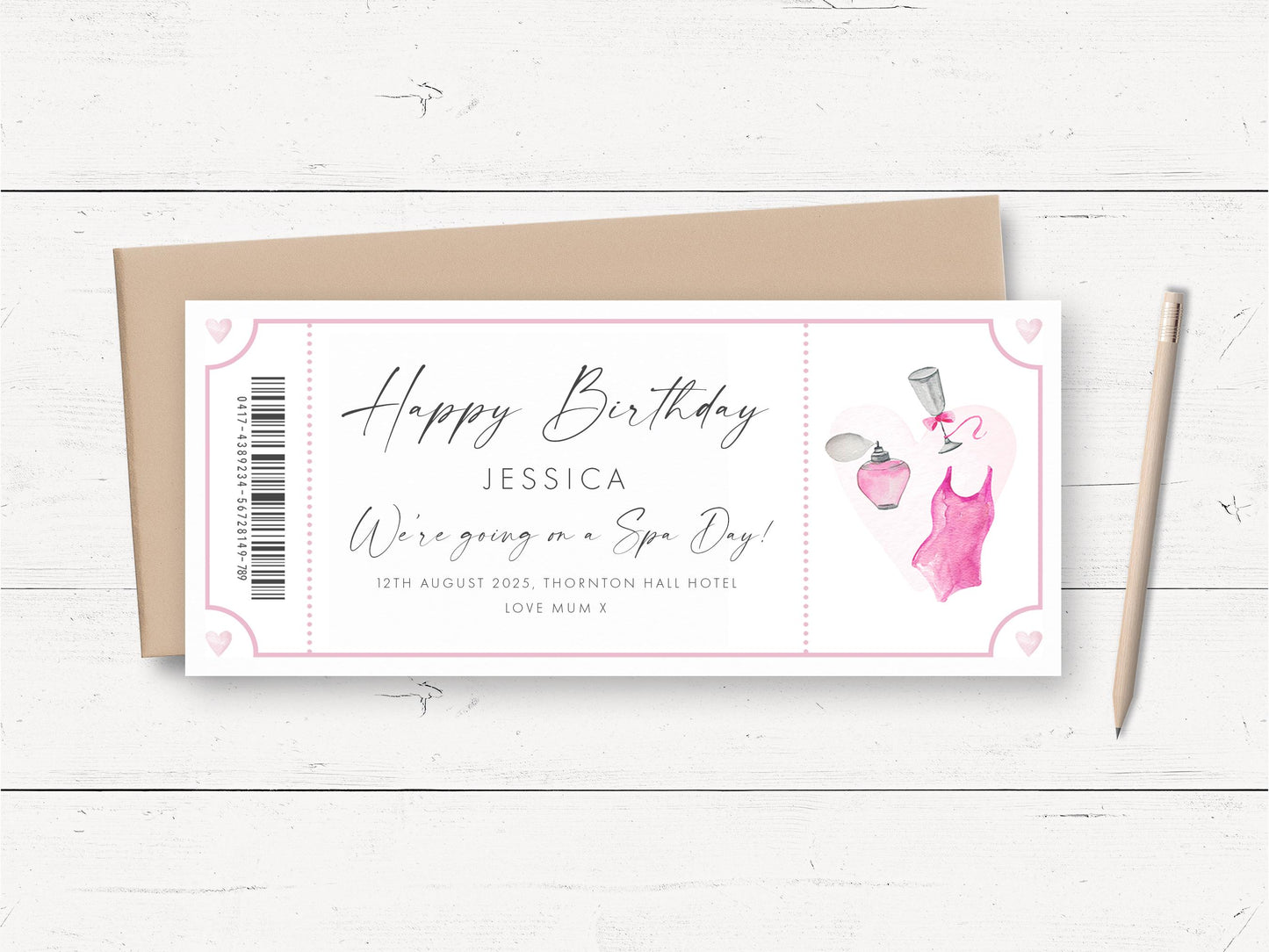 A birthday card with a pink and white color scheme, featuring a design with a perfume bottle and a pink dress. The card is placed on a white wooden surface, accompanied by a pencil and a brown envelope.