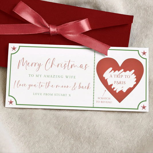 a red envelope with a red ribbon and a white card with a red heart and text on it, placed on a beige surface.