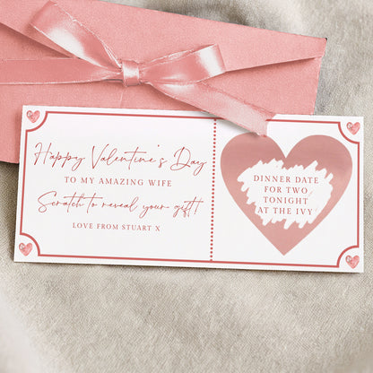 a Valentine's Day card with a pink ribbon and a heart-shaped design. The card has a message that reads "Happy Valentine's Day to my amazing wife. Surprise to reveal your gift! Love from Stuart X."