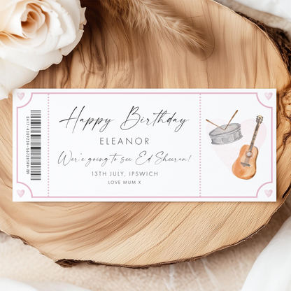 A birthday ticket with a guitar and rose on it, placed on a wooden surface.