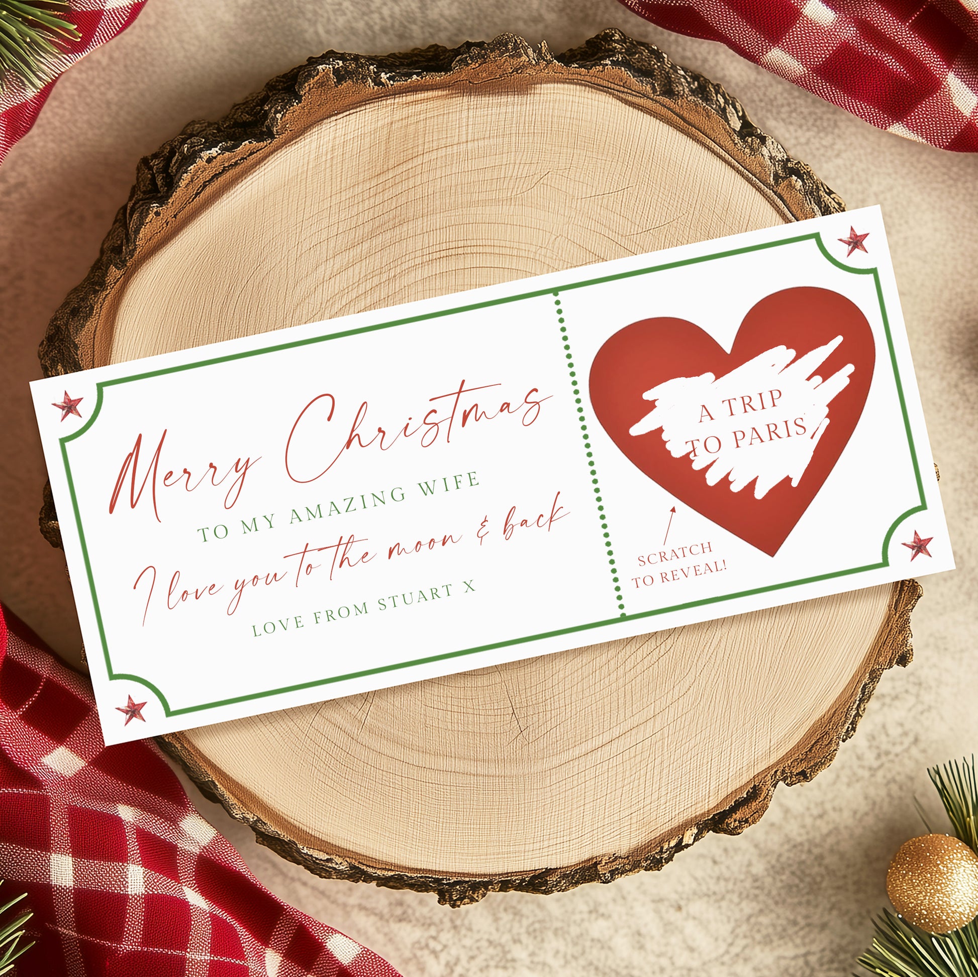 A Christmas-themed gift card with a heart-shaped design and a message for a wife, placed on a wooden surface with Christmas decorations.
