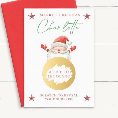 A Christmas card featuring a Santa Claus illustration, with the text "Merry Christmas Charlotte" and "A TRIP TO LEGOLAND" along with a gold circle and a red star.