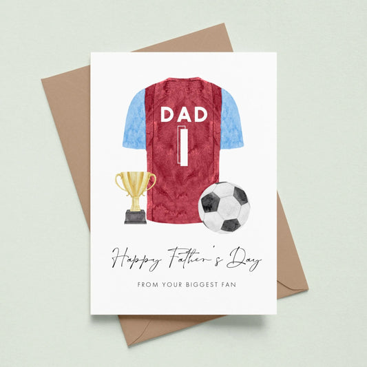 A greeting card with a soccer jersey, trophy, and soccer ball, along with the text "Happy Father's Day" and "From your biggest fan" printed on it.
