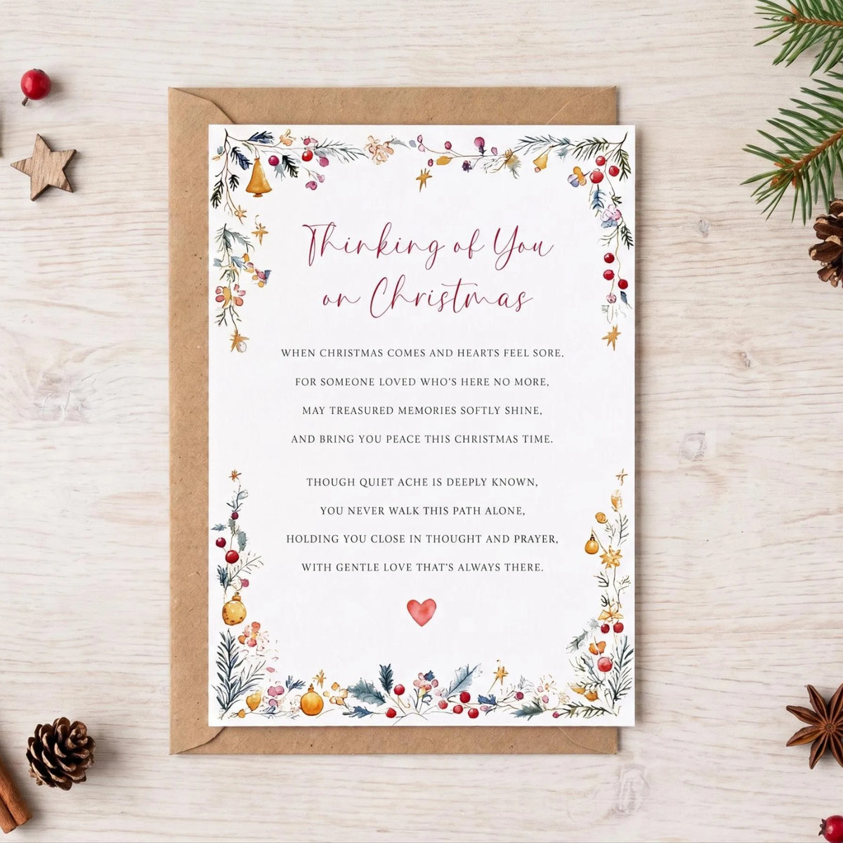 a Christmas card with a thoughtful message, surrounded by holiday decorations such as pine branches, pine cones, and berries.