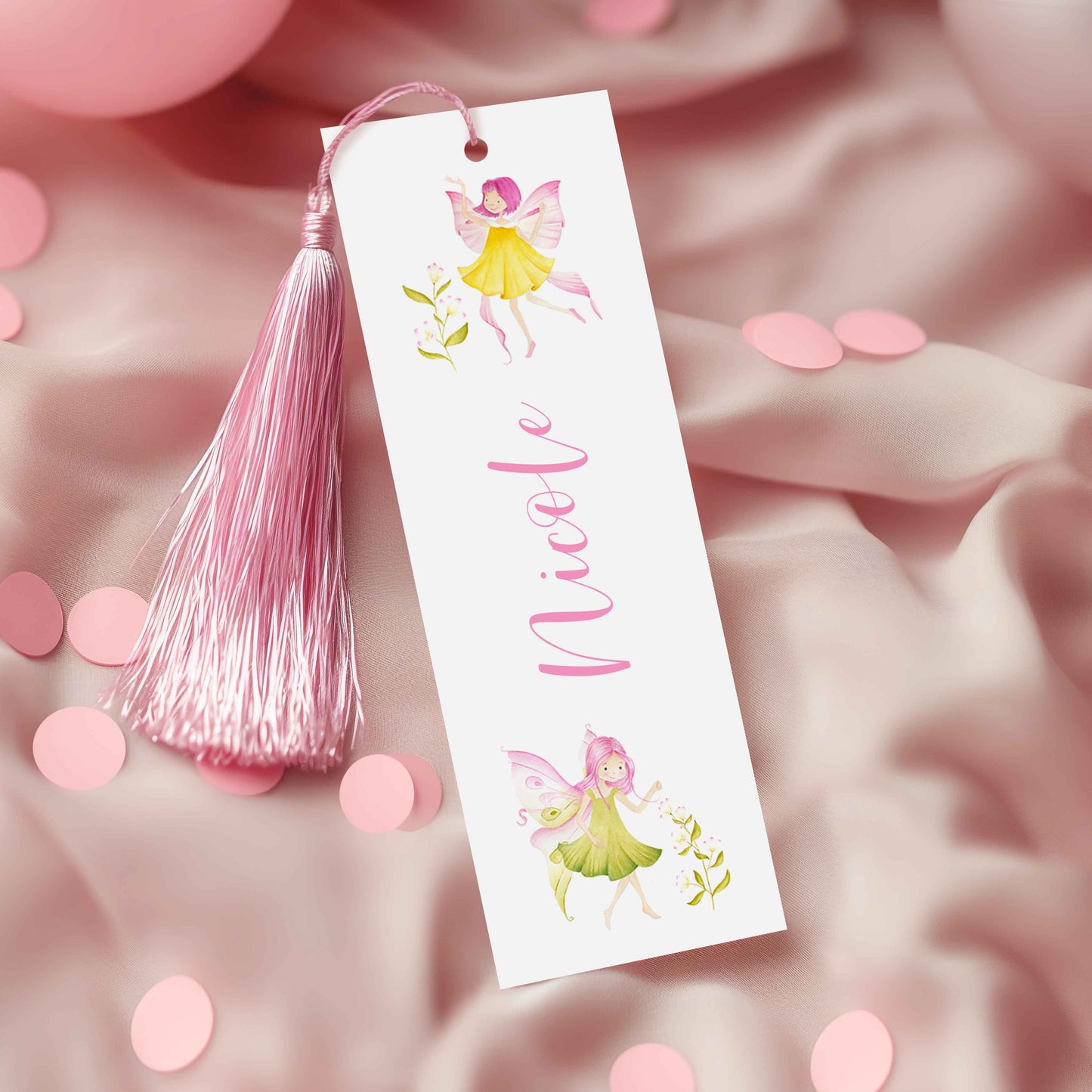 A white bookmark with a pink tassel and illustrations of fairies on a pink background.