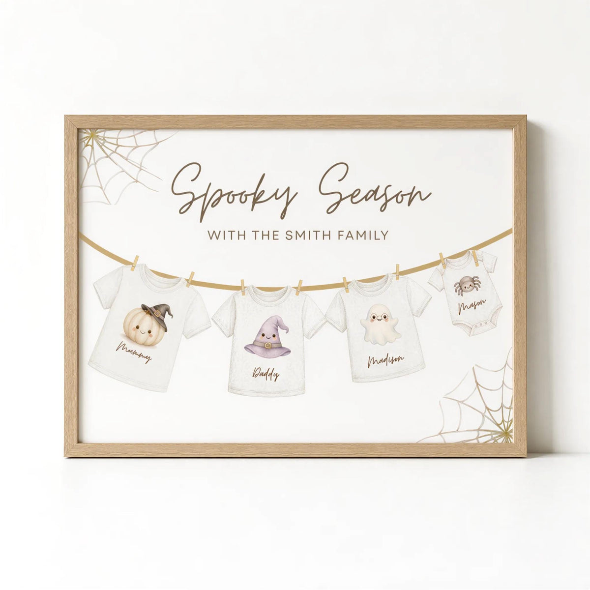 The image is a framed print featuring a spooky season theme with illustrations of Halloween-themed t-shirts hanging on a clothesline.