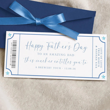 A blue envelope with a blue ribbon tied around it, and a white card with blue text on it, placed on a beige surface.