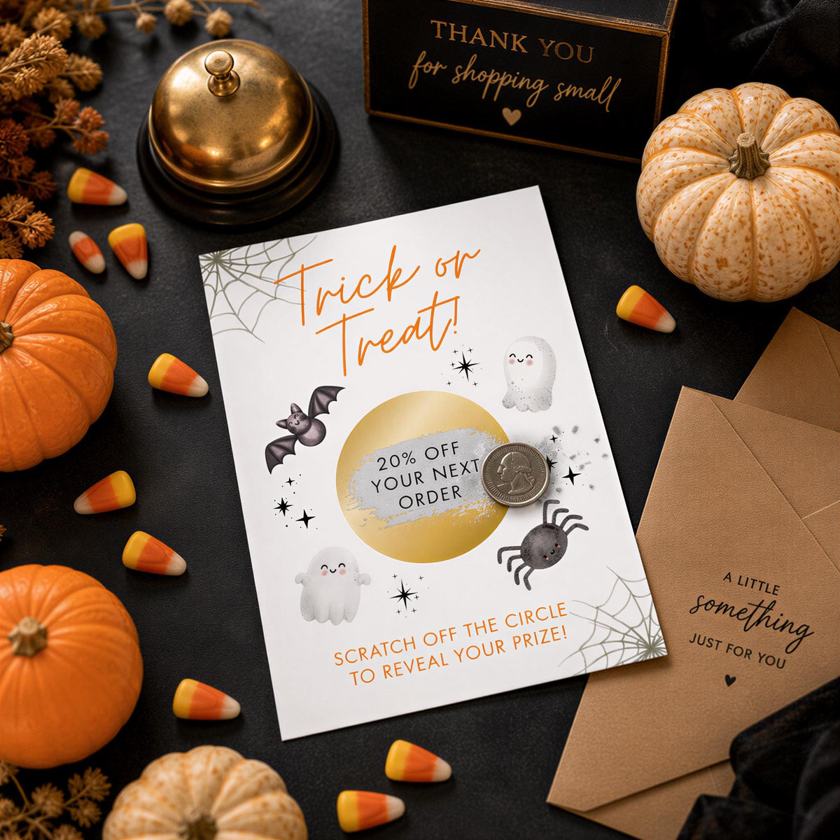 Halloween decorations and candy, including a card with a 20% off offer, a bell, and a small pumpkin.