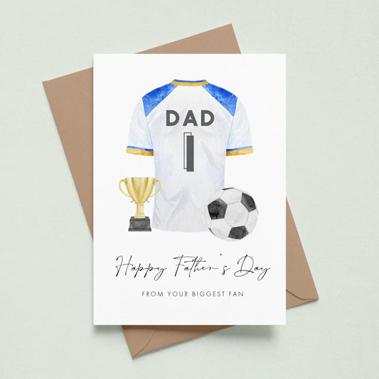 A greeting card with a soccer jersey, trophy, and soccer ball, along with the text "Happy Father's Day" and "From your biggest fan" printed on it.