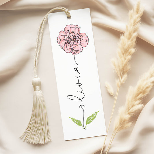 A white bookmark with a pink flower illustration and the name "Livra" written on it, along with a white tassel.