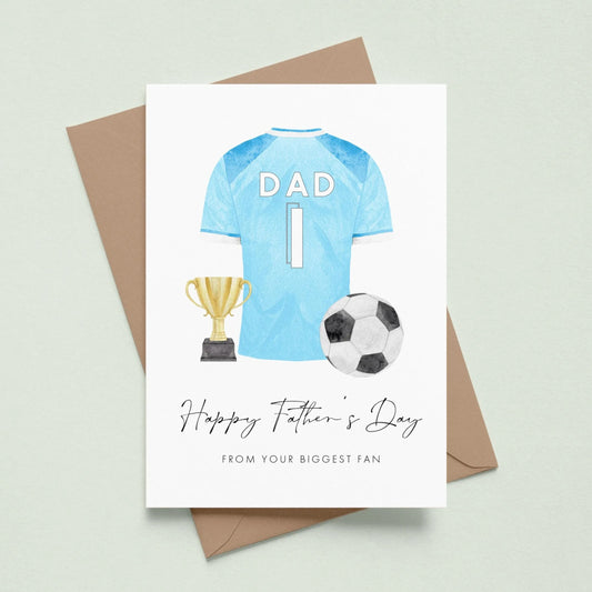A greeting card with a soccer jersey, trophy, and soccer ball, along with the text "Happy Father's Day" and "From your biggest fan" printed on it.