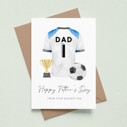 A greeting card with a soccer jersey, trophy, and soccer ball, along with the text "Happy Father's Day" and "From your biggest fan" printed on it.