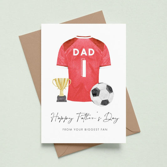 A greeting card with a soccer jersey, trophy, and soccer ball, along with the text "Happy Father's Day" and "From your biggest fan" printed on it.