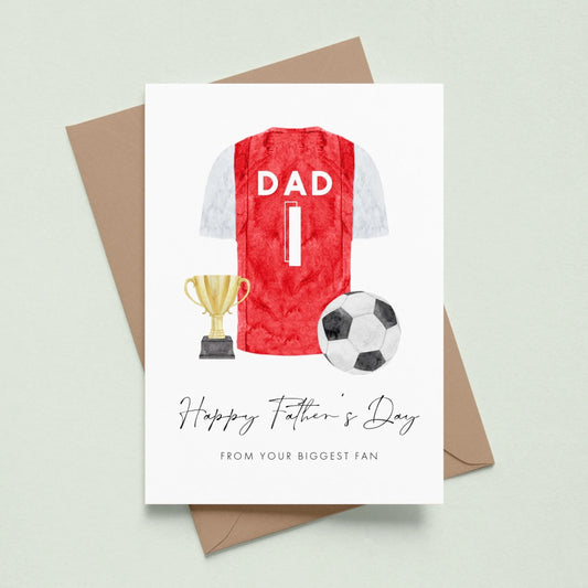A greeting card with a soccer jersey, trophy, and soccer ball, along with the text "Happy Father's Day" and "From your biggest fan" printed on it.