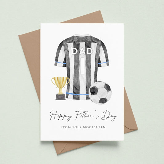 A greeting card with a soccer jersey, trophy, and soccer ball, along with the text "Happy Father's Day" and "From your biggest fan" printed on it.