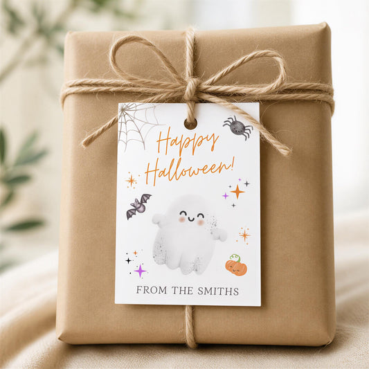 A brown gift box wrapped in brown paper, tied with a brown string, and a white tag attached to it with a bow. The tag has a Halloween-themed design, including a ghost, spider, and pumpkin.